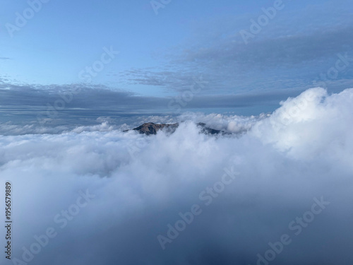 Canvas Print Cloud sea filling the valley with a distant peak rising above soft layers