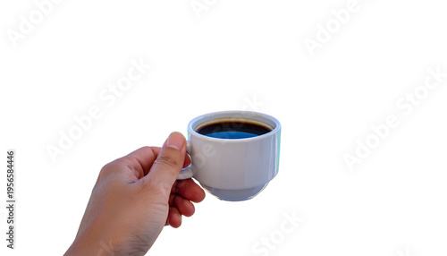 Hand holding a small white mug filled with dark coffee, against a black background