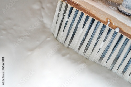 Traditional application of white limewash on a wall with a large brush