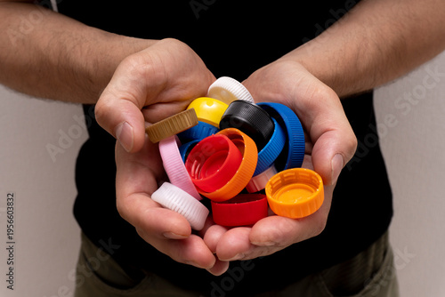 Closeup at caucasian hands full of colorful plastic bottle cups,