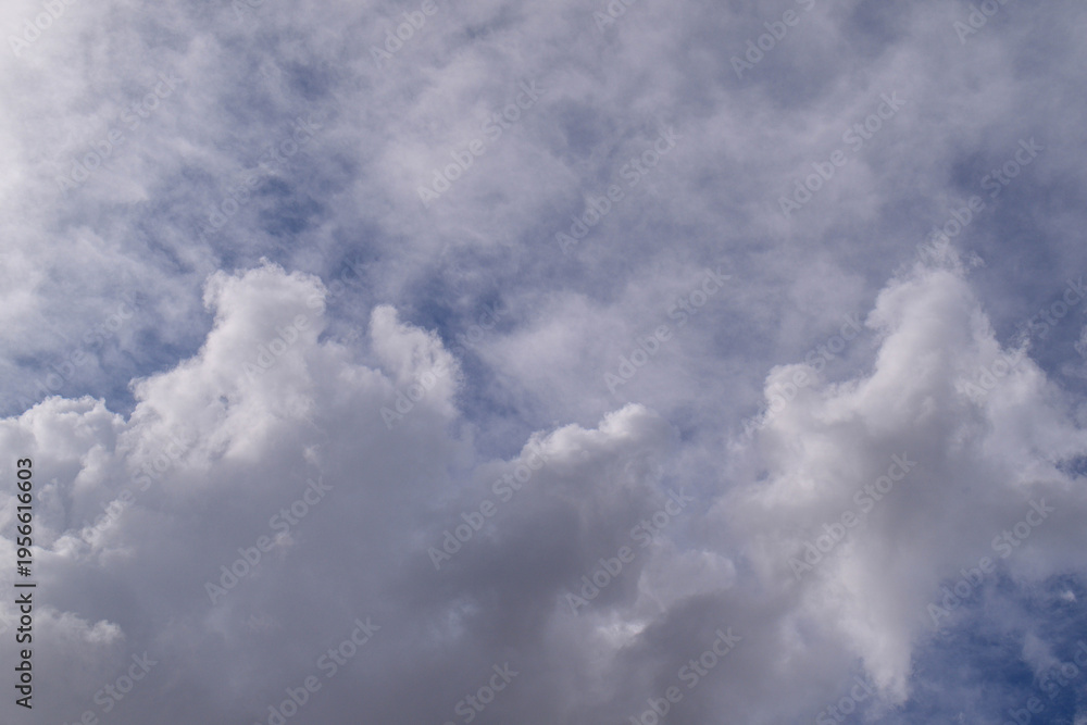 Fototapeta premium Vast, puffy white clouds drift across a clear blue expanse