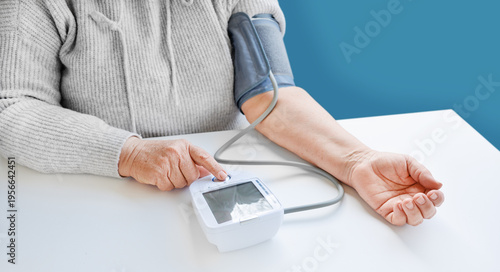 Slika na platnu Old woman measuring blood pressure with an electric digital tonometer