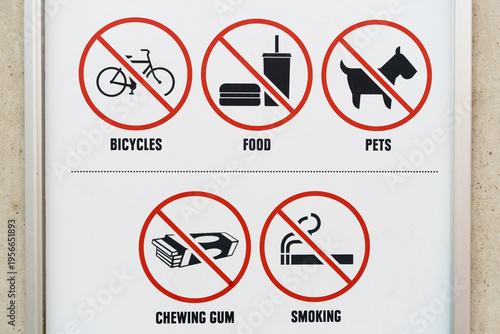 This sign on the wall shows several objects representing activities that are prohibited. Not allowed is for example, riding a bicycle, eating, dogs, smoking, and chewing gum.