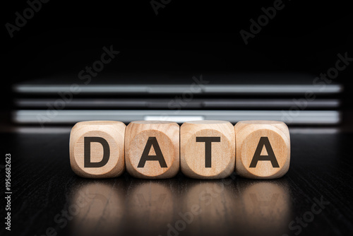 DATA word on wooden blocks with reflection and blurred laptops background.