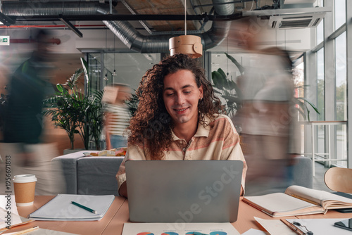 Man working on laptop in busy office