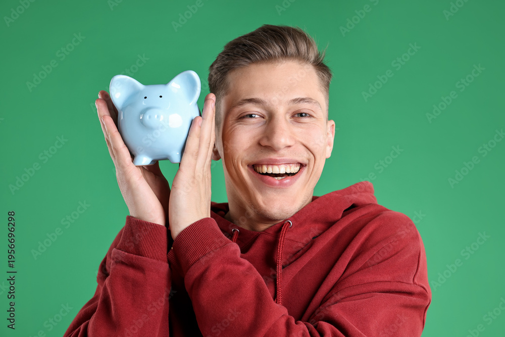 Obraz premium Happy man with piggy bank on green background