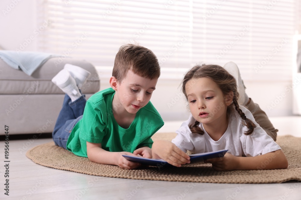 Obraz premium Cute little kids reading book on floor indoors