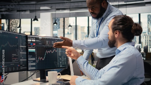 Foto Prop firm staff members communicate at PC desk to ensure smooth trading operations