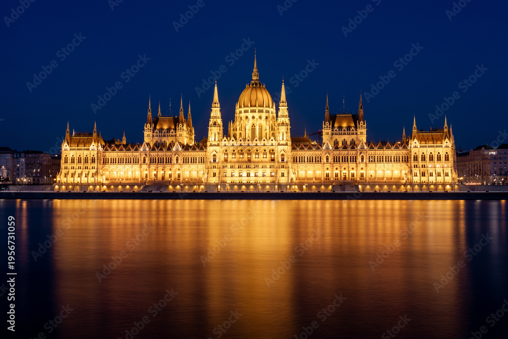 Fototapeta premium The Budapest Parliament building at night on the Danube river bank