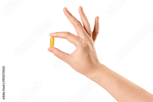 Close-up of a hand holding a single fish oil capsule or vitamin supplement  isolated on white background. health, wellness, and medical