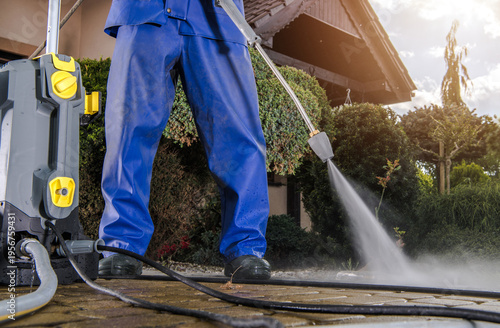 Man Cleans Patio With Pressure Washer on Sunny Day