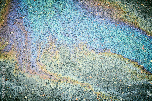 Cuadro en lienzo Oil, gasoline, and water mixing on a wet asphalt road surface, forming a vibrant