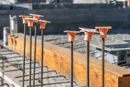Quadro su tela Construction site, with orange rebar caps on steel rebar stub ups in a reinforced concrete wall, foundation to protect construction workers and building materials