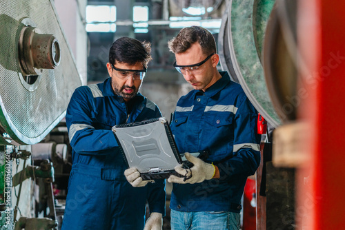 Factory Technicians Reviewing Digital Machine Diagnostics in Traditional Metal Workshop