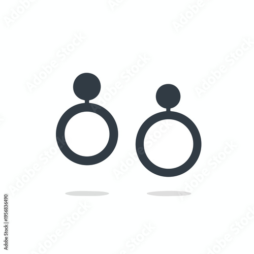 A pair of dark grey, modern circular earrings hang against a white background