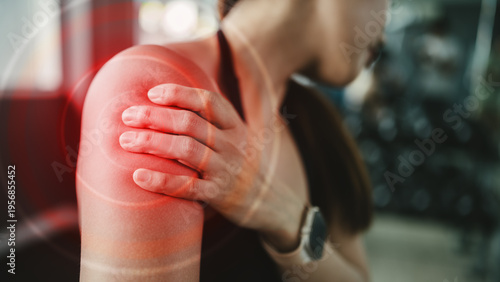 Female athlete holding painful shoulder with red inflammation highlight. Concept of muscle strain, soft tissue tear, sports trauma, acute injury, overexertion, recovery, and physical therapy.