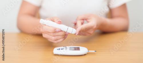 Hand using lancet pen on finger with Blood drop glucose testing or Diabetes checking by digital blood glucose meter. blood sugar level, Diabetes Day, Glycemia, Hypoglycemia, Hyperglycemia and insulin