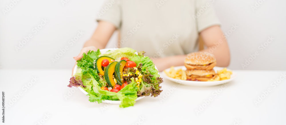 Naklejka premium happy woman choose vegetables Salad. Healthy and Unhealthy Food Choice, Comparison of Calories and Nutrition of vegetables and Hamburger. diet planning, weight loss control, junk food and lifestyle