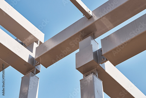 Abstract exterior detail of structural canopy beams against clear blue sky