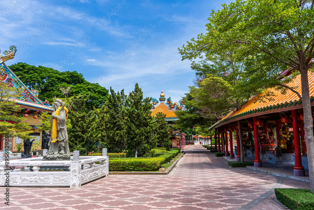 Obraz premium Colorful Chinese temple roofs and garden path surrounded by greenery at Suphan Buri shrine