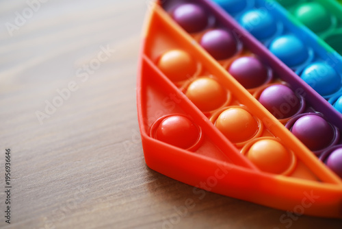 Colorful Rainbow Pop It Fidget Toy on Wooden Table - Sensory Stress Relief and Fun