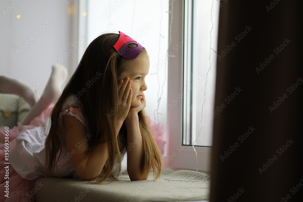 Fototapeta premium Young Girl in Princess Costume Daydreaming by Window, Wearing Purple Mask, Children's Imagination, Indoors