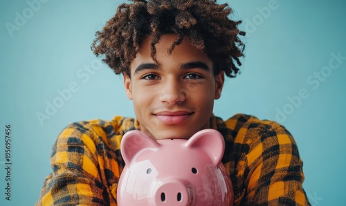 Young man sitting with a large pink piggy bank on a blue background, representing the concept of saving money and financial security, Generative AI