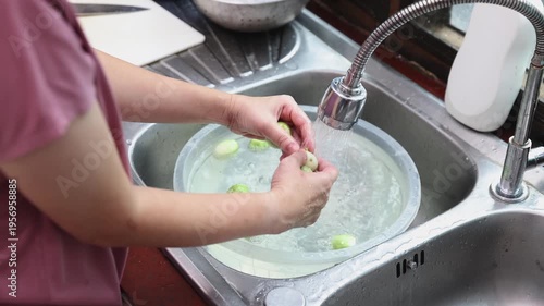 Woman washing and cleaning eggplant, preparing ingredients for a homemade dinner. A glimpse into traditional cooking and culinary preparation.
