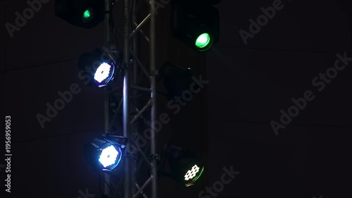 Colorful LED spotlights hanging on a metal truss tower blinking and shining in the dark. Concert stage lighting and entertainment event background concept.