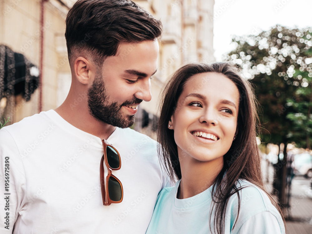Fototapeta premium Smiling beautiful woman and her handsome boyfriend. Woman in casual summer jeans clothes. Happy cheerful family. Female having fun. Sexy couple posing in the street at sunny day