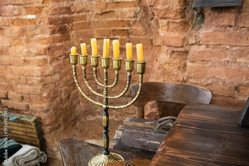 Candle holder with candles arranged in a row on a table in a brick setting during evening time