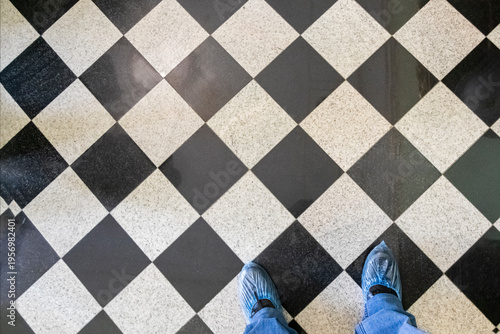 Person standing on checkered floor with blue shoes in indoor space during daylight