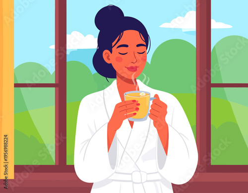 A woman in a white bathrobe enjoying a hot steaming drink by a window with a green outdoor view.