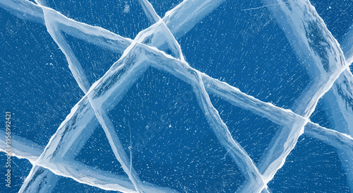 Close-up view of intricate cracks forming geometric patterns in clear blue frozen ice, showcasing natural beauty and texture.