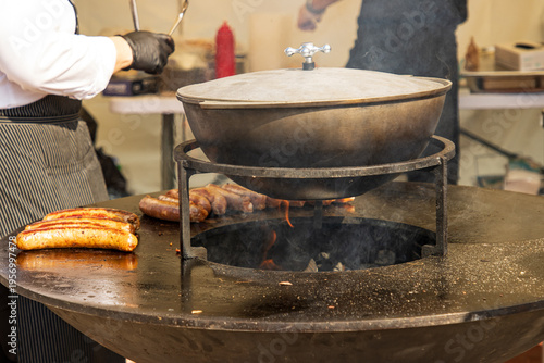 A man is cooking sausages on a grill