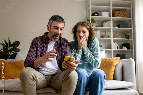 Excited couple receiving surprising news on smartphone
