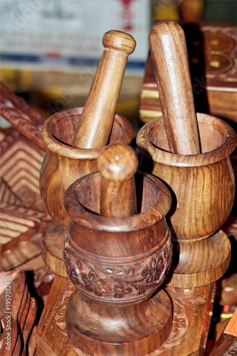 Three wooden mortars and pestles with detailed carvings, showcasing artisanal craftsmanship and rich wood texture.