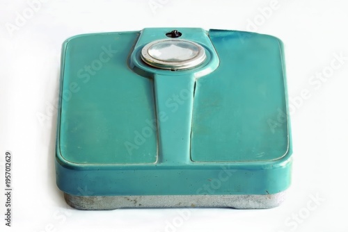 Vintage teal bathroom scale with a large circular dial, showcasing classic design and aging marks, resting on a light surface.