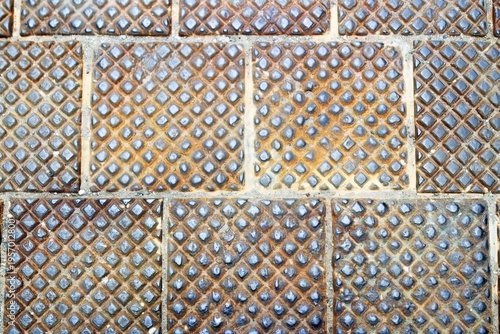 Weathered metal tiles with a diamond pattern, showcasing rust patches and a grid arrangement, creating a unique visual texture