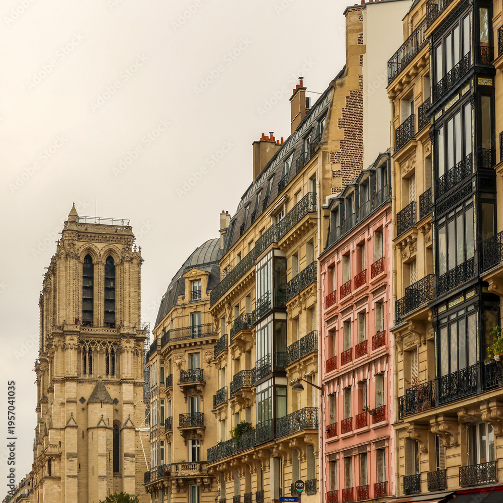 Fototapeta premium Notre Dame Cathedral tower rising above classic Haussmann buildings and Parisian street architecture