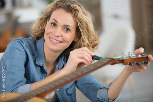 woman as trainee cleaning guitar in guitar maker workshop