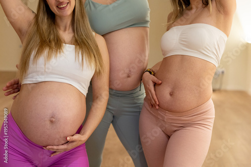 Pregnant women showing bare bellies practicing prenatal yoga