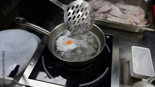 Chef cooking a perfect poached egg in a restaurant kitchen saucepan