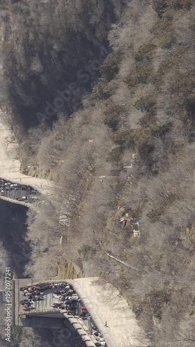 vertical crowded people visit The Great Wall of China among mountain range hill in winter dry winter weather under sunny blue sky, ancient great wall with wide path and crowded people walking on  wall