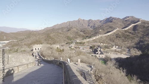 The Great Wall of China among mountain range hill in winter dry winter weather under sunny blue sky, famous tourist attraction of China in winter ancient city great wall with wide path on the wall