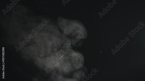 Slow motion steam rising from boiling water over black background