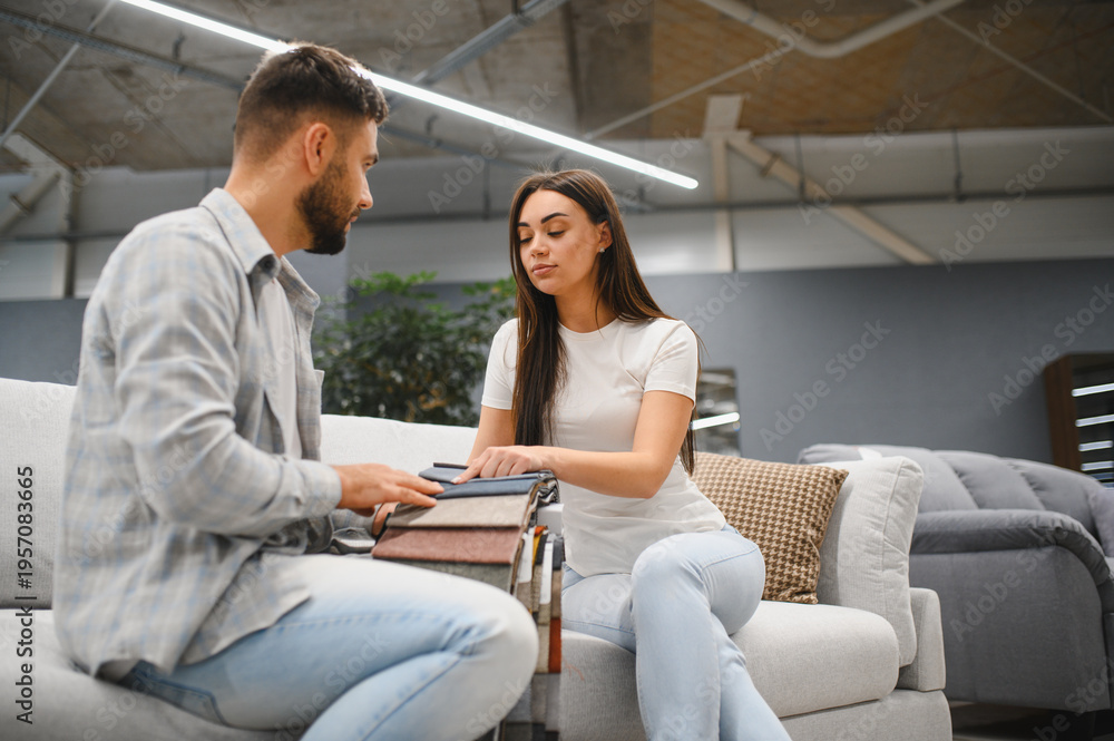 Fototapeta premium Couple choosing fabric samples for new sofa at furniture store