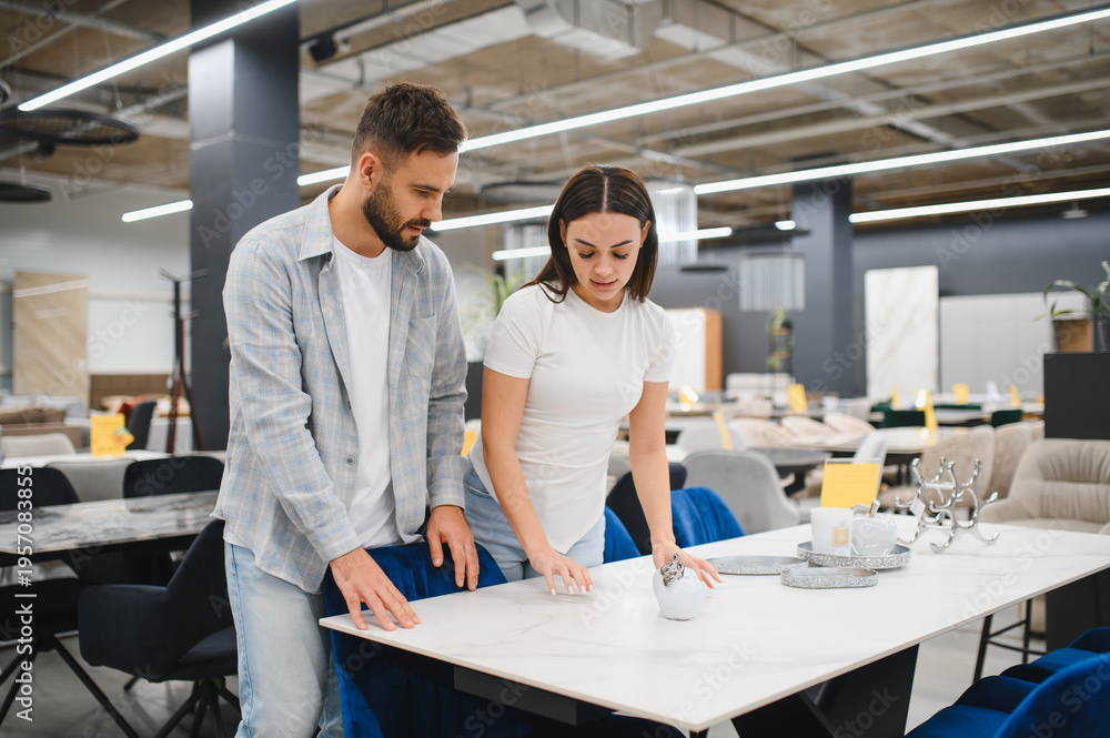 Obraz premium Young couple choosing dining table at furniture store
