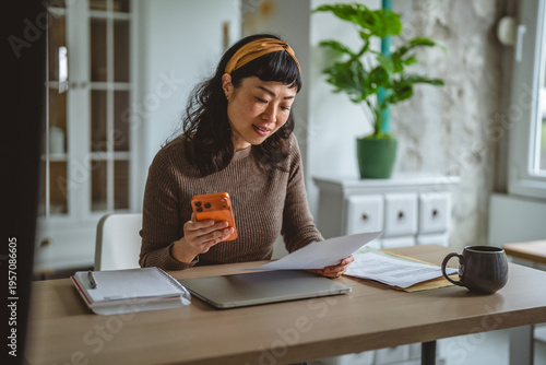 Fotografie Woman managing finances at home office using smart phone
