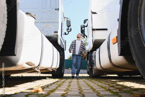 Fotografia Truck driver walking between semi trucks inspecting fleet